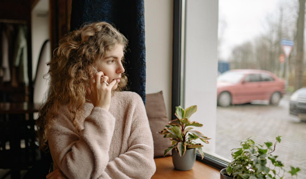 Woman sits at window, talking on phone