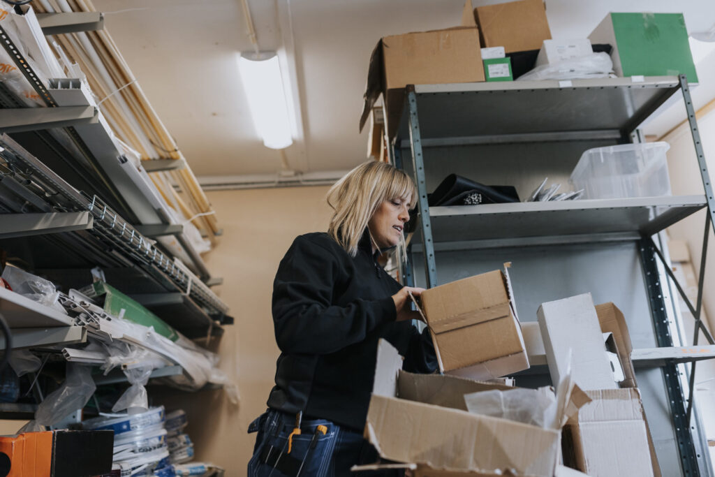 Manufacturing worker picking up cardboard box with paperwork.