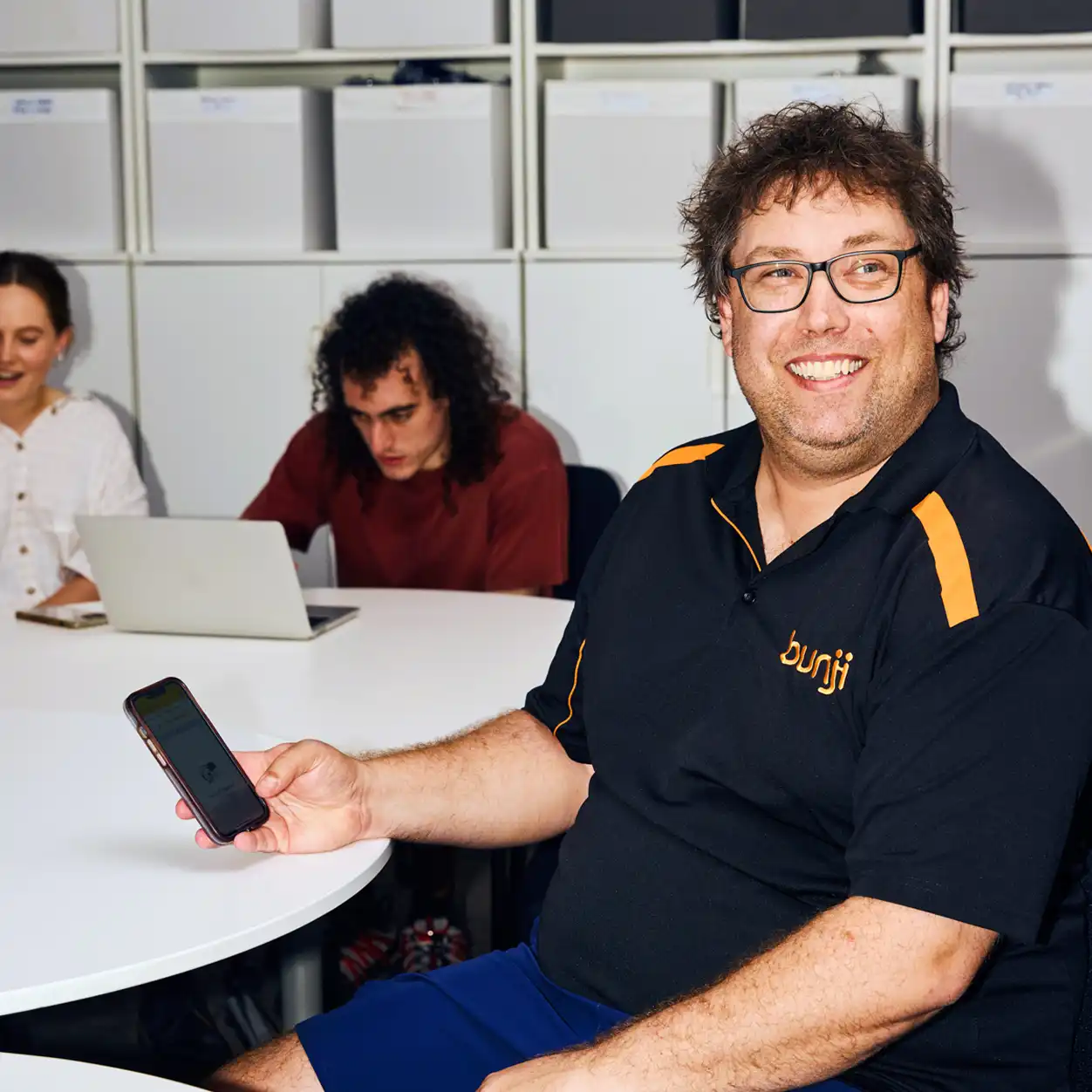 A man sitting at a table, looking thoughtfully at a notebook in front of him.