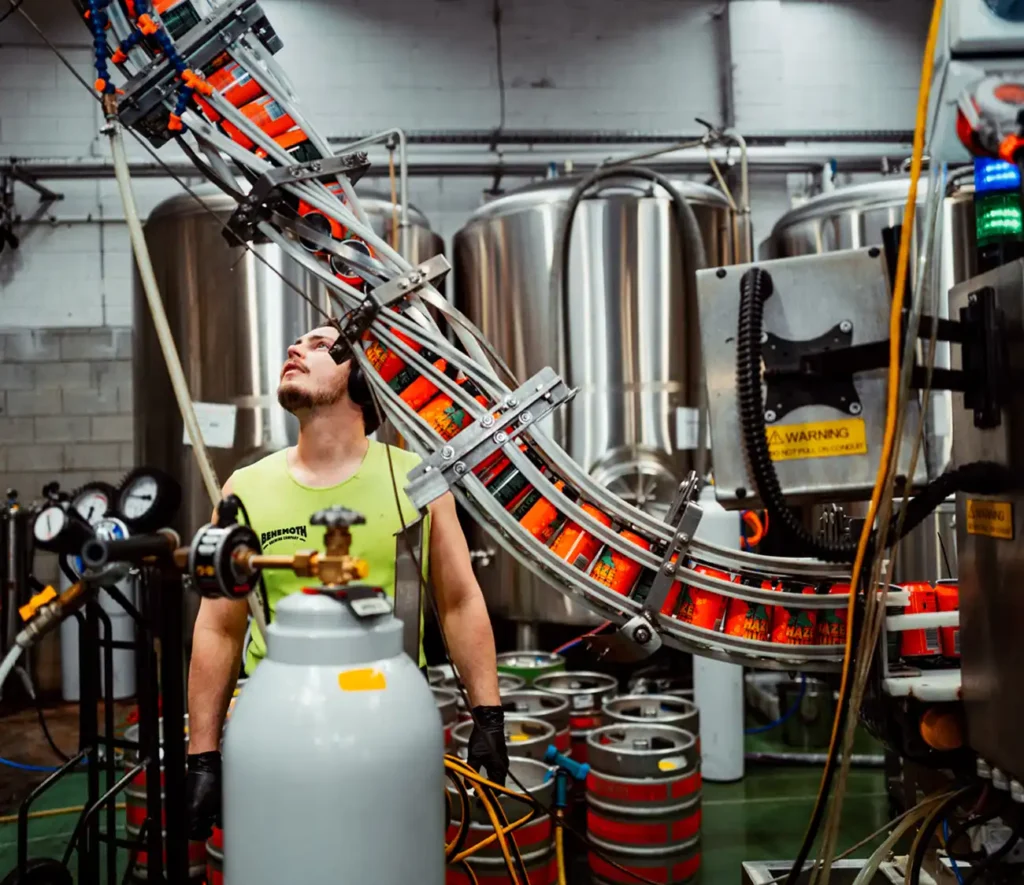 A man operates a machine in a factory, focused on his task amidst industrial equipment and tools.