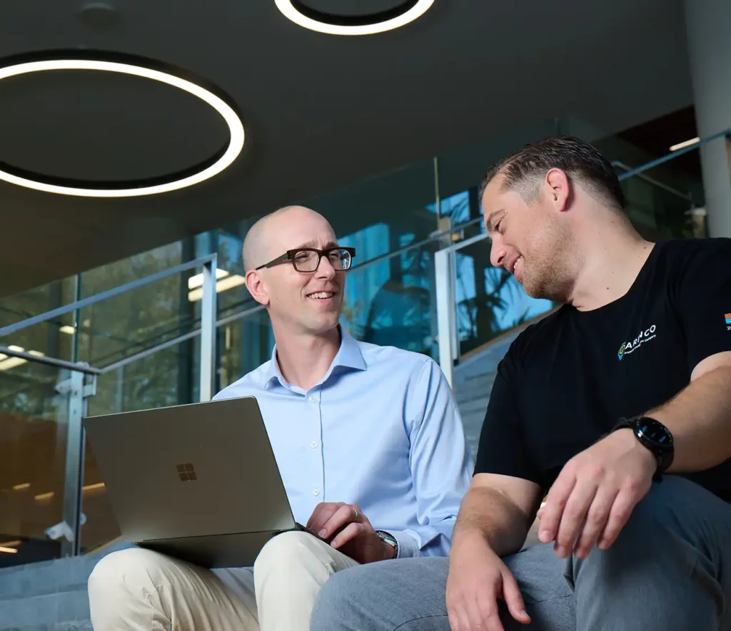 Two men sitting on outdoor stairs, engaged in conversation, with a casual and relaxed atmosphere.