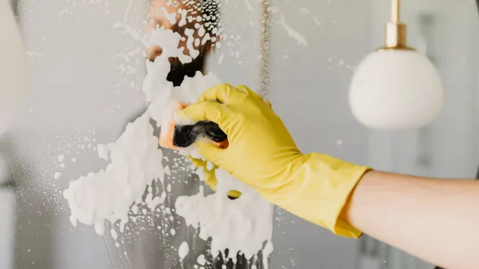 A gloved hand scrubbing the mirror clean