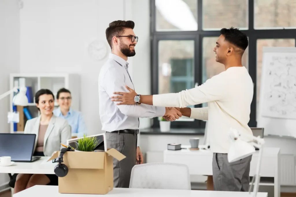 Two colleagues shaking hands and smiling at each other