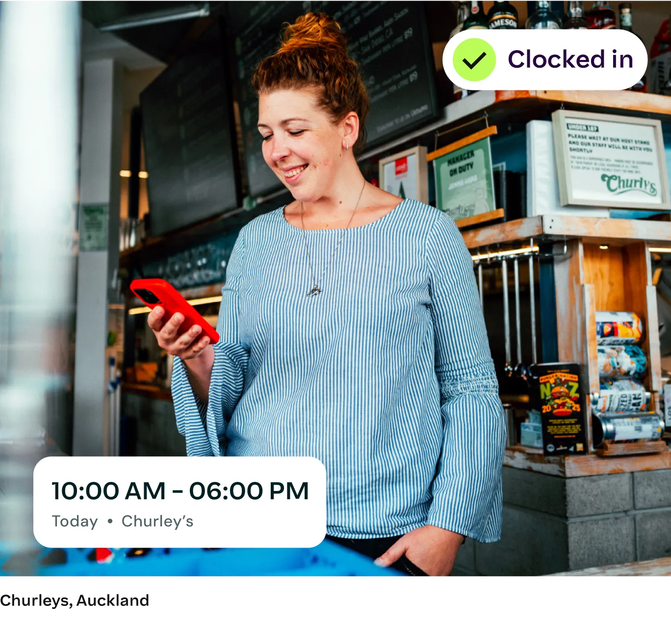 smiling female employee at Churley's in Auckland using her smartphone to clock in for her 10 AM to 6 PM shift, representing local New Zealand businesses supported by Employment Hero's managed payroll services.
