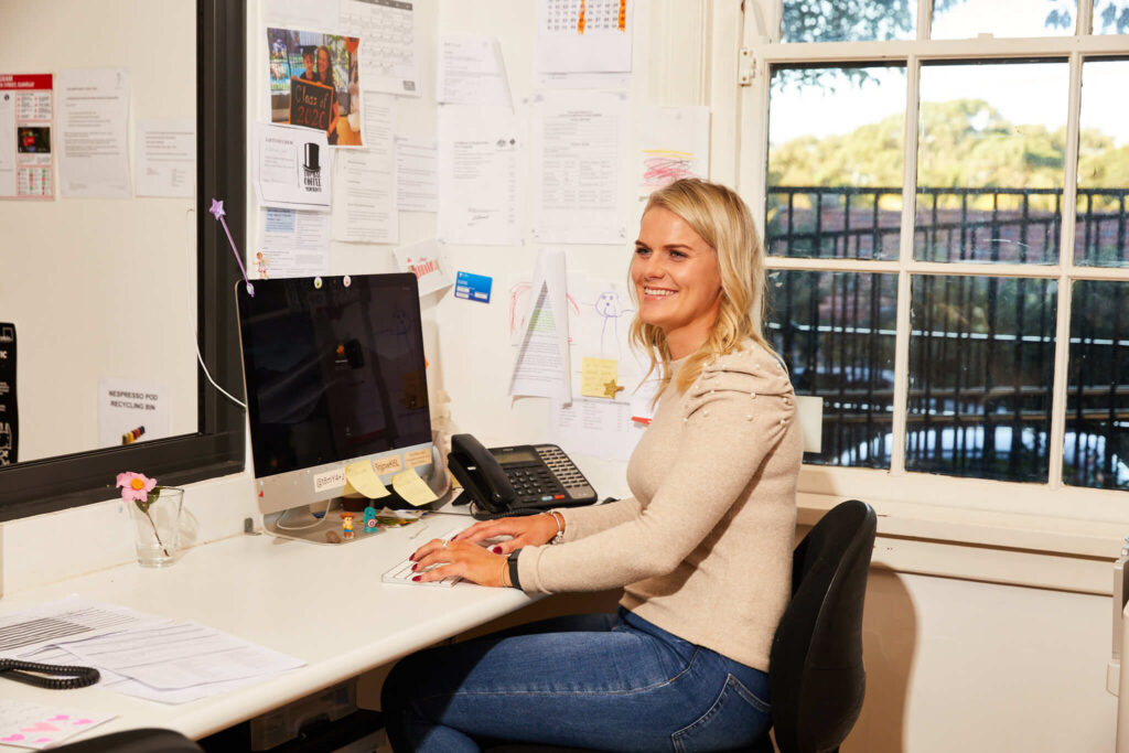 A woman smiling happily on her desk