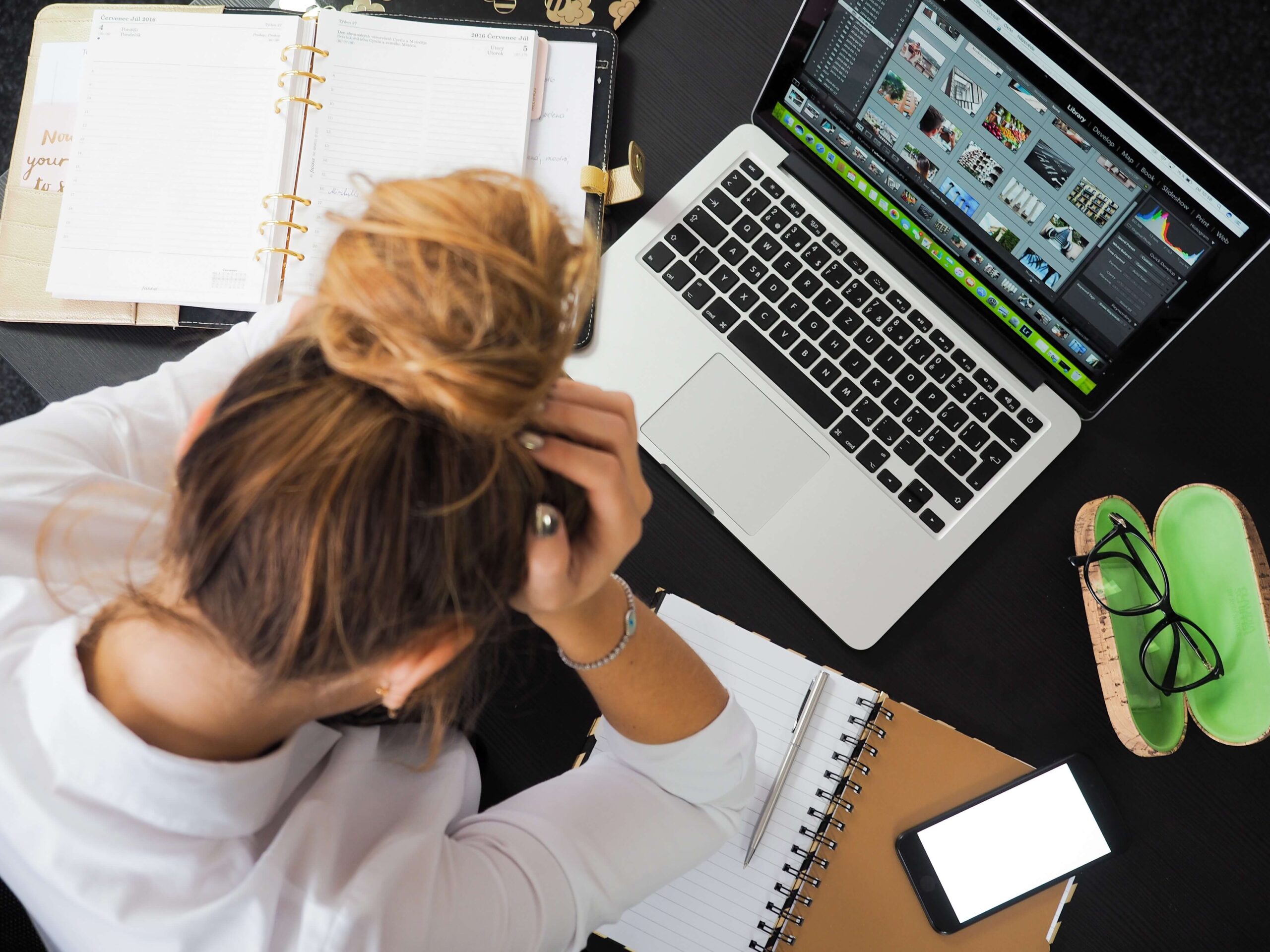 woman holding her head in frustration at her work desk