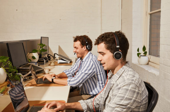 image of two males sitting at their desk working - value from employment hero