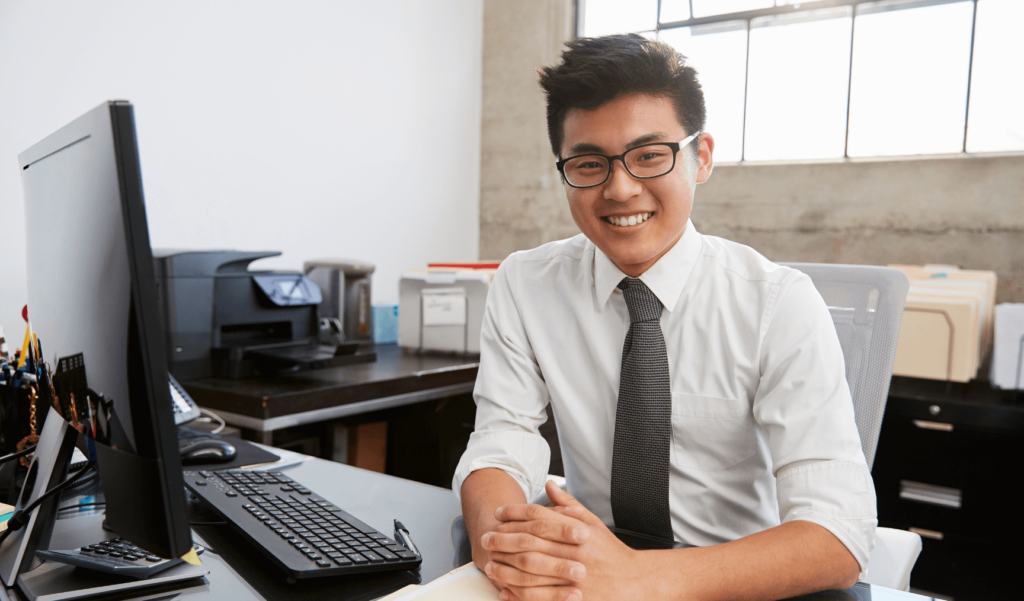 a man wearing glasses and smiling at work