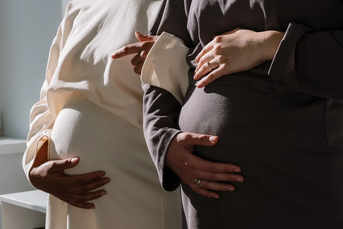 two pregnant ladies holding their bellies