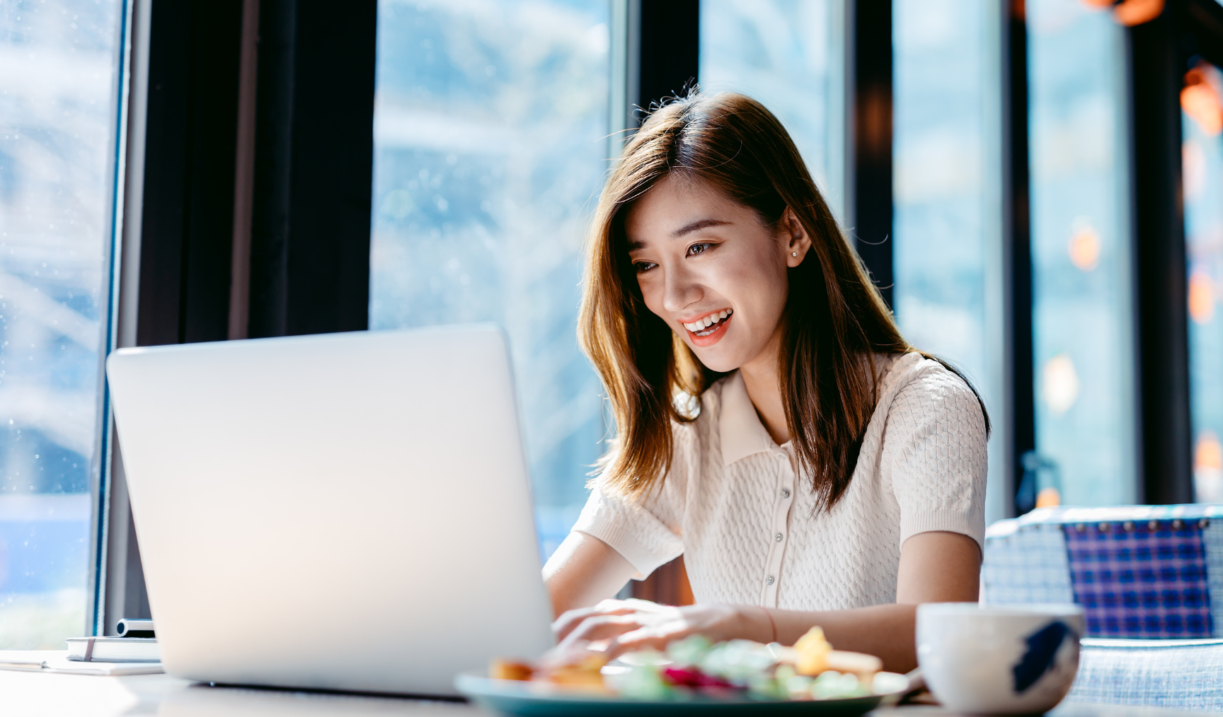 woman smiling while typing on her laptop