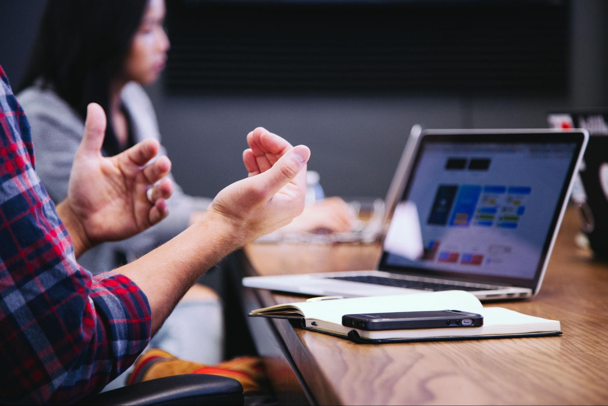 man with hand gestures in front of laptop