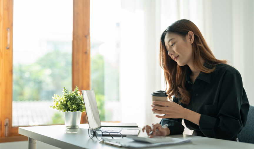 woman holding coffee cup and working on laptop