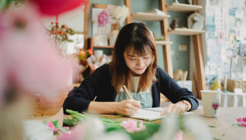 woman writing on a notebook in a florist