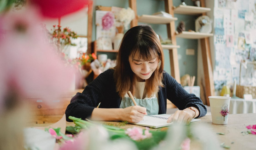 woman writing on a notebook in a florist