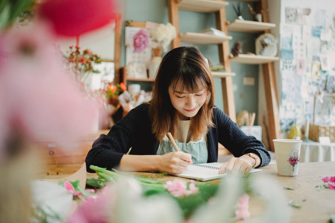 woman writing on a notebook in a florist