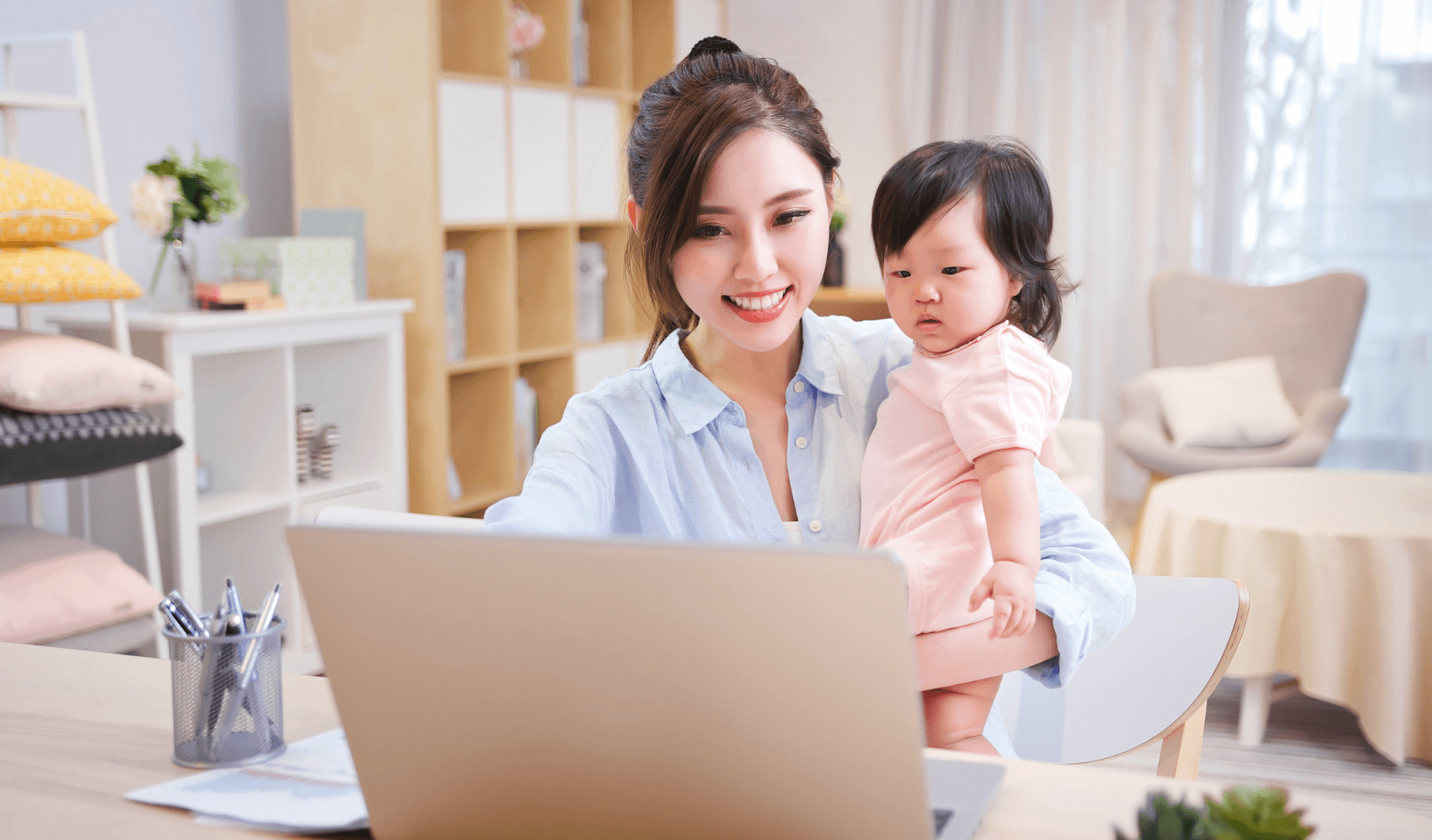 mum holding a baby while working with a laptop