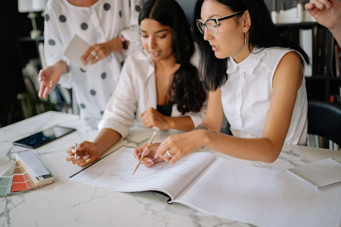 two employees discussing over a stack of papers on the desk