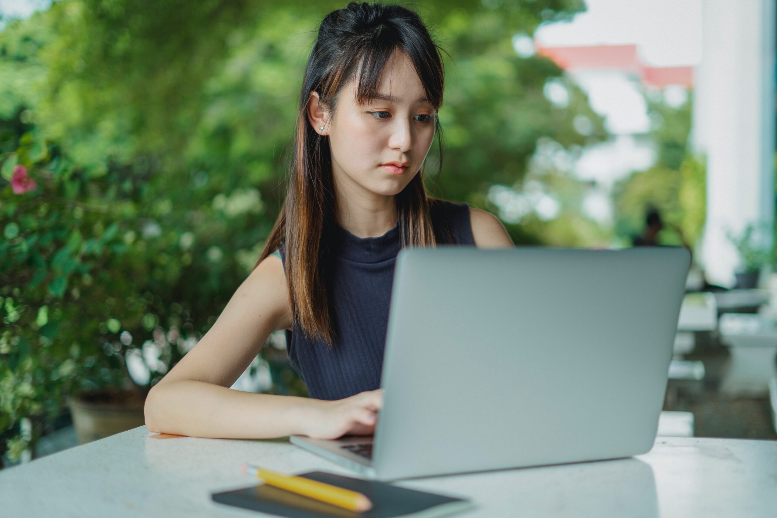 asian woman typing on her laptop in an outdoor space