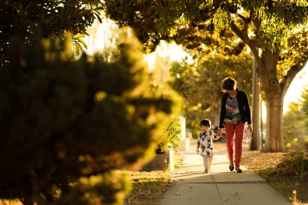 Mother and daughter walking down a sunny street
