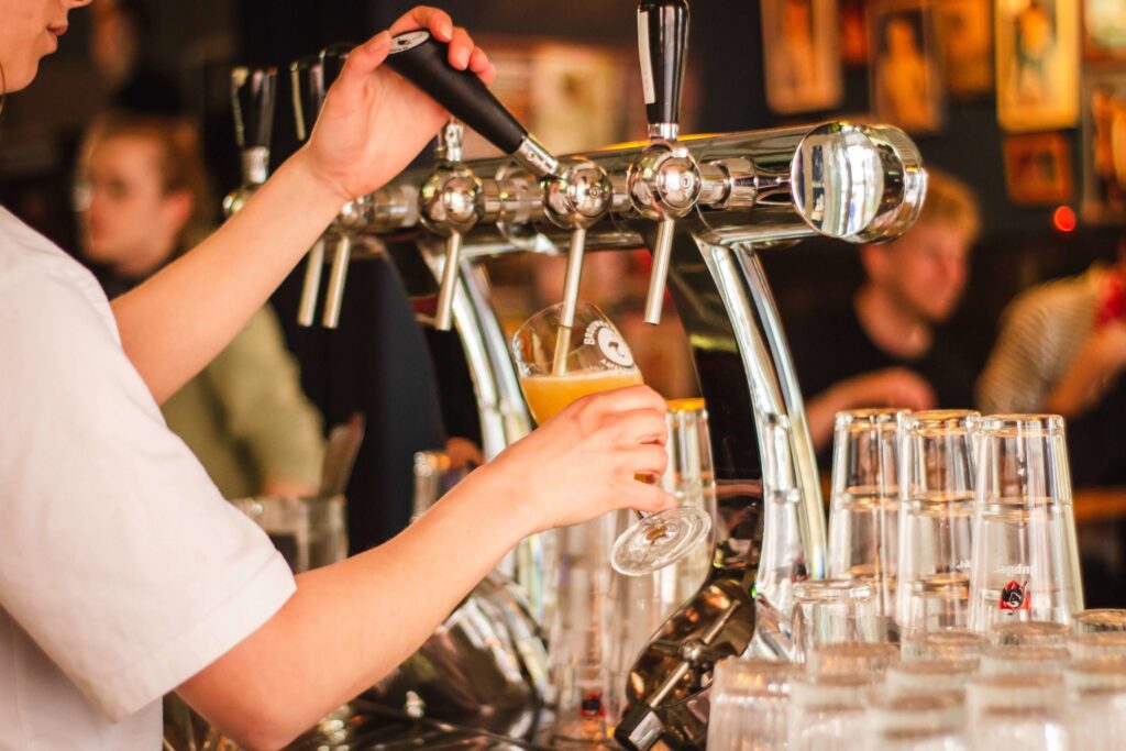 Person pouring a beer in pub