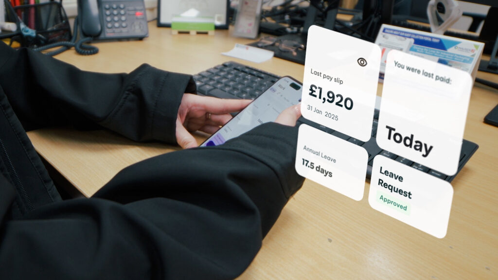 Person holding a smartphone at a desk with a digital interface overlay showing pay info, leave balance, and a leave request status.