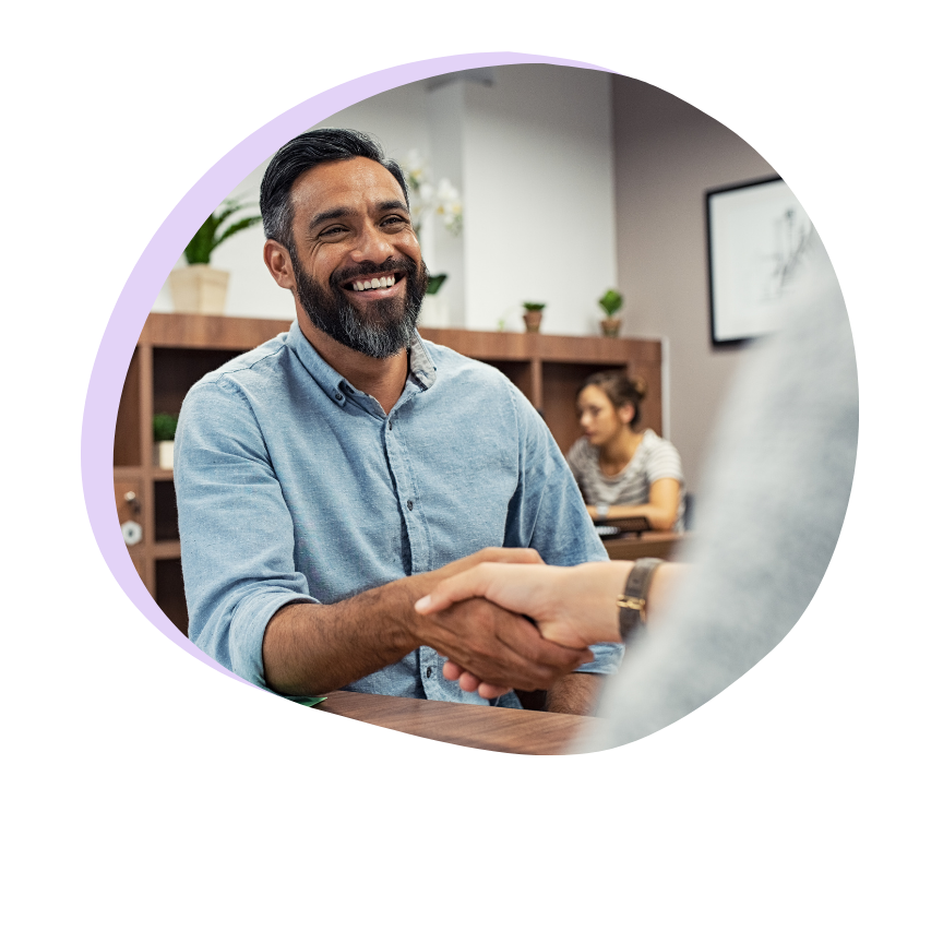 A man smiling while shaking hands.
