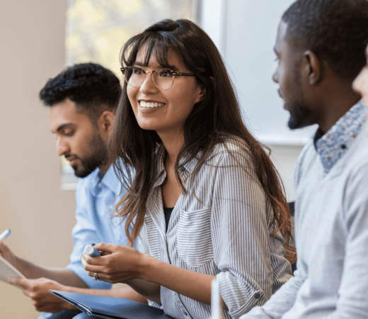 A group of professionals having a discussion, with a smiling woman speaking while others listen attentively.