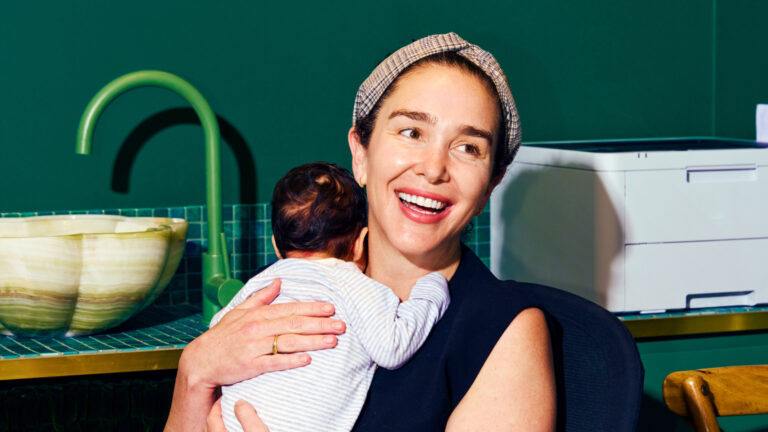 A smiling woman happily carrying her baby.