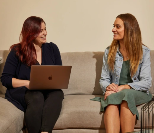 Two women talking on a couch.