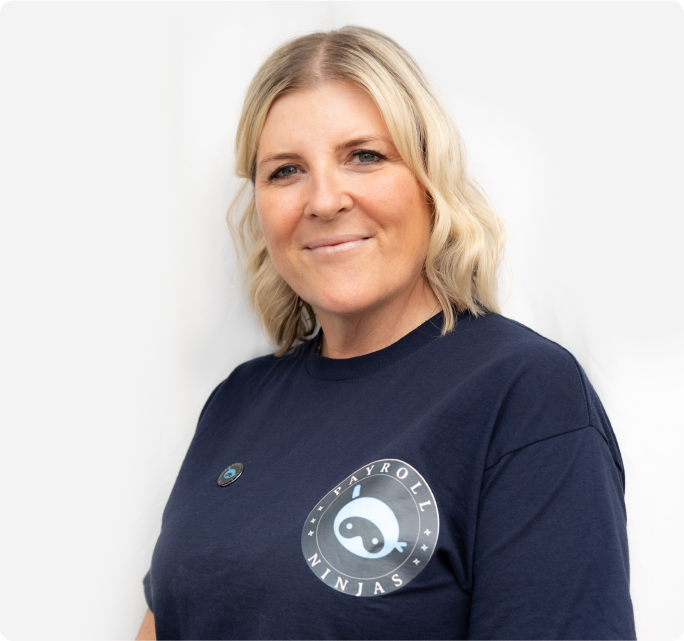 A woman with blonde hair and a friendly smile wears a navy "Payroll Ninjas" shirt. She stands against a plain white background, conveying confidence.