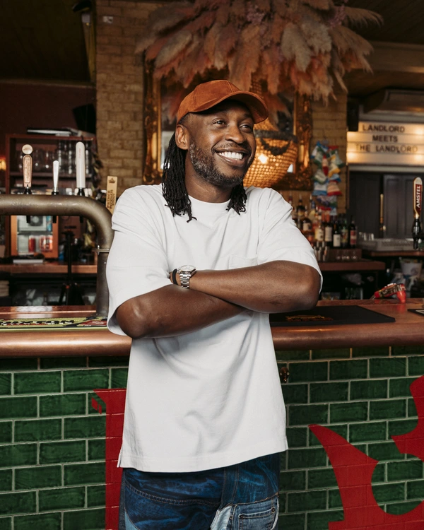 A man wearing white shirt smiling while crossing his arms.