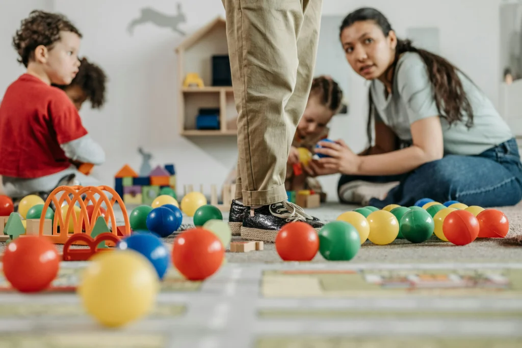 Children playing with colorful balls and toys in a nursery setting, representing how childcare vouchers support early learning environments.