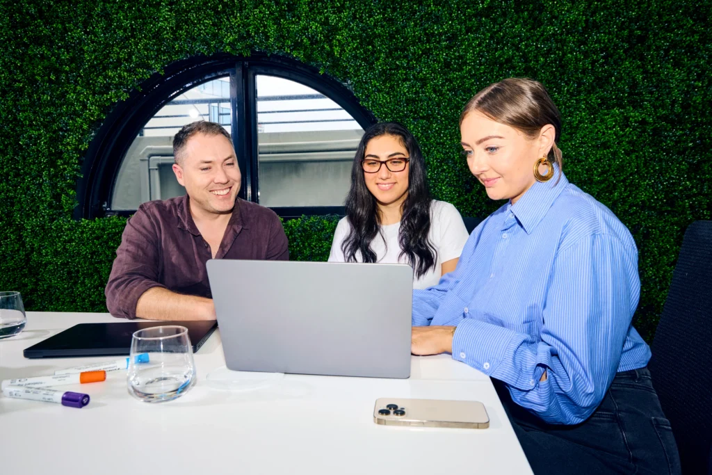 HR team collaborating on a laptop, leveraging AI in HR for talent acquisition and employee analytics.