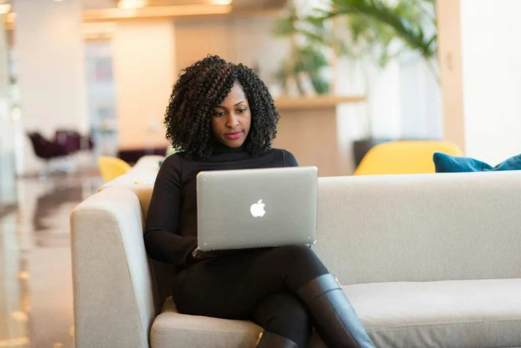 Professional woman accessing her HR data via employee self service from a laptop in a lounge area.