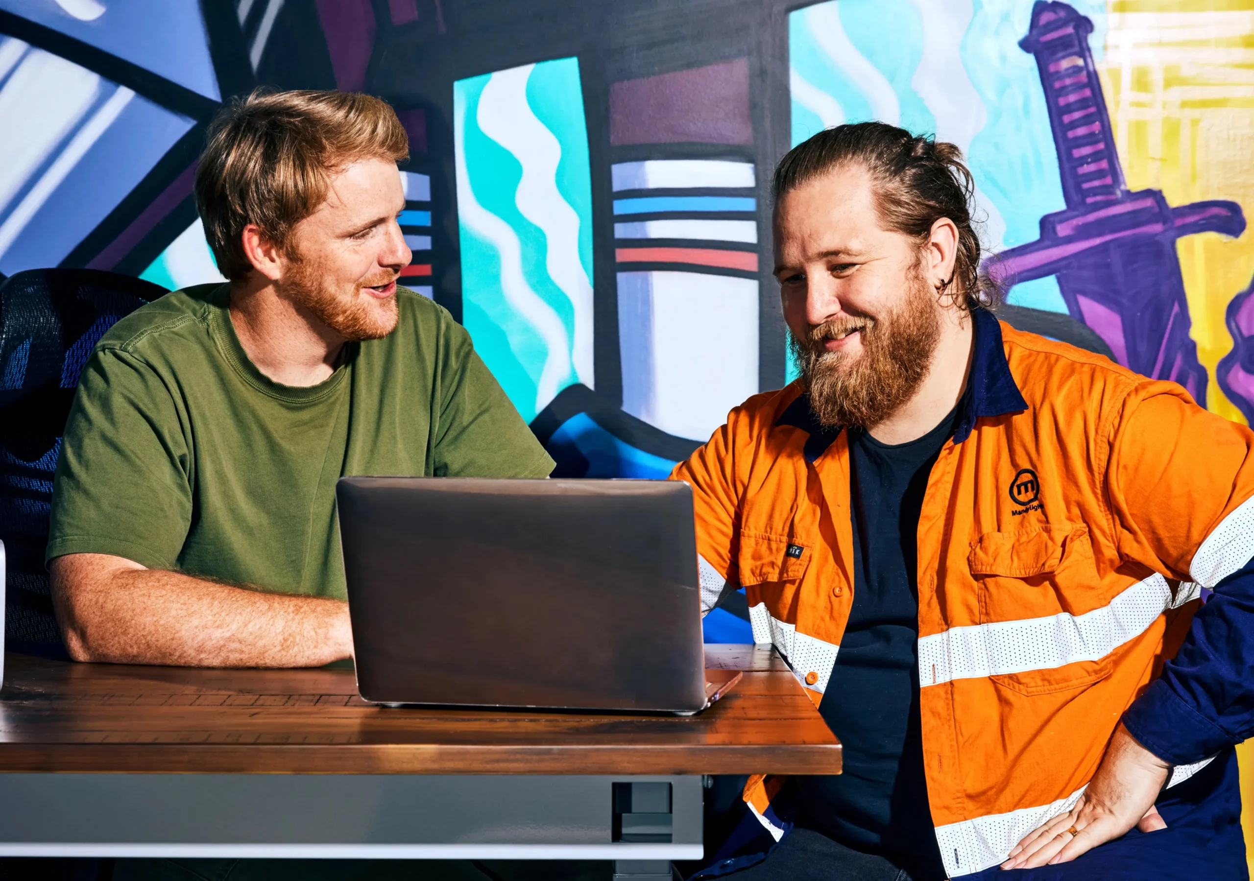 Blue-collar workers reviewing training modules on a laptop, enabled by AI in HR learning and development programs.
