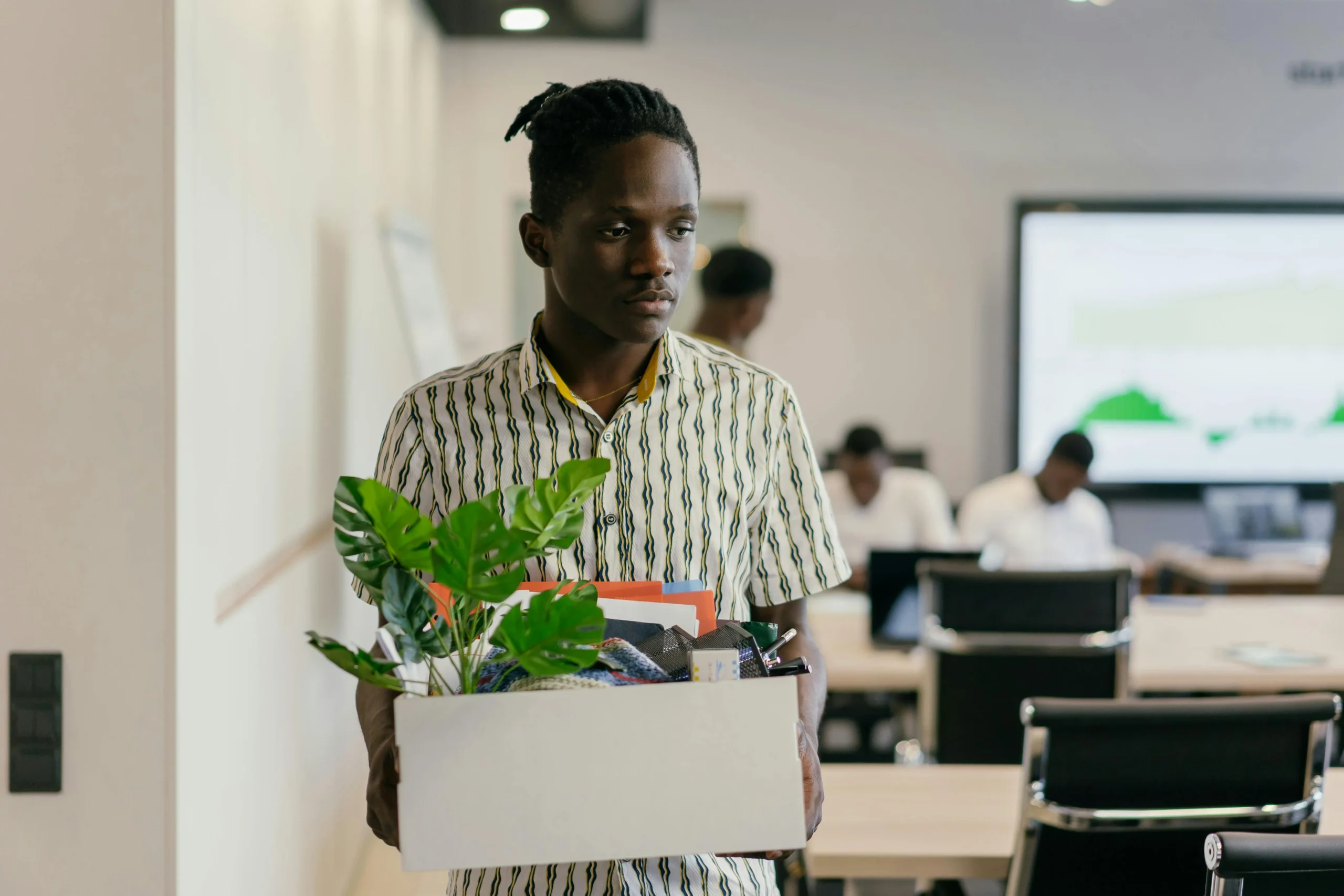 Person holding box of personal items in modern office, suggesting job change or transition