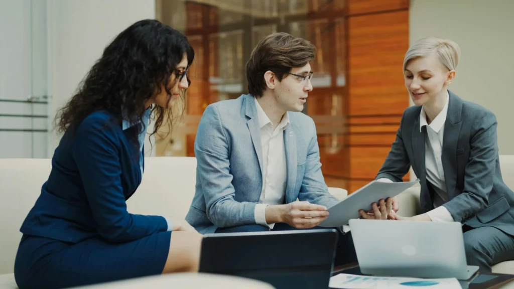 Three colleagues in formal office attire, discussing work