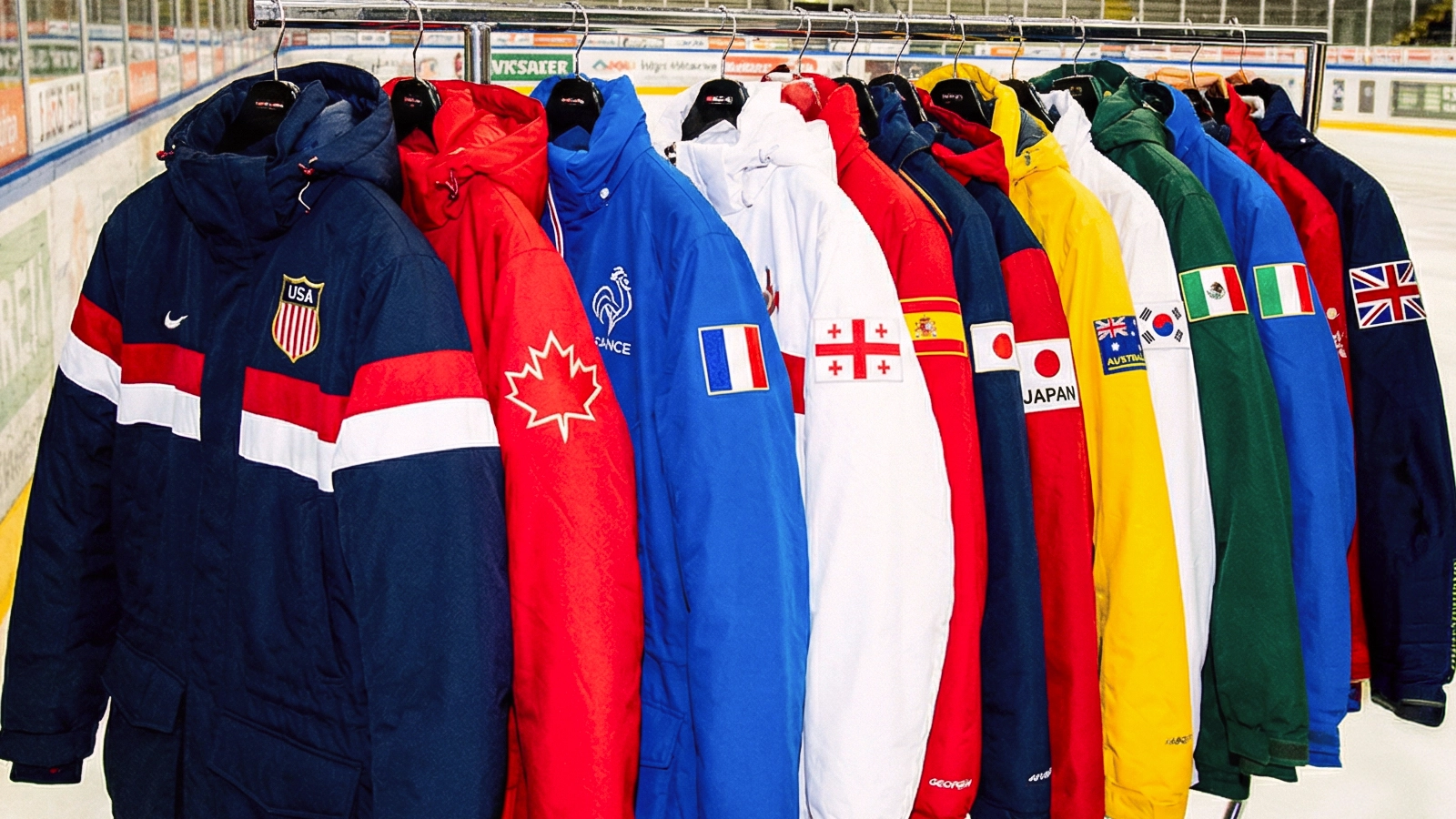 A row of colorful winter jackets with various national flags, including the USA, Canada, and France, hang on a rack in an ice rink, conveying a sense of international unity.