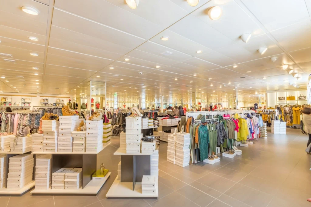 Bright, spacious clothing store with neatly arranged racks and stacks of shoeboxes. Warm lighting creates a welcoming and organized atmosphere.