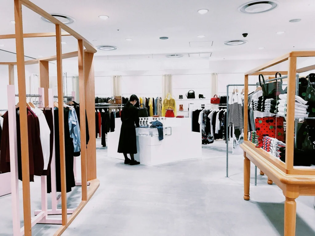 A bright clothing store with neatly arranged racks of colorful garments and accessories. A person browses items, creating a calm, inviting atmosphere.
