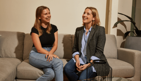 two women on couch at work talking - hiring new employees