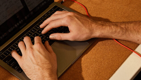 Close up of man's hands typing on a laptop
