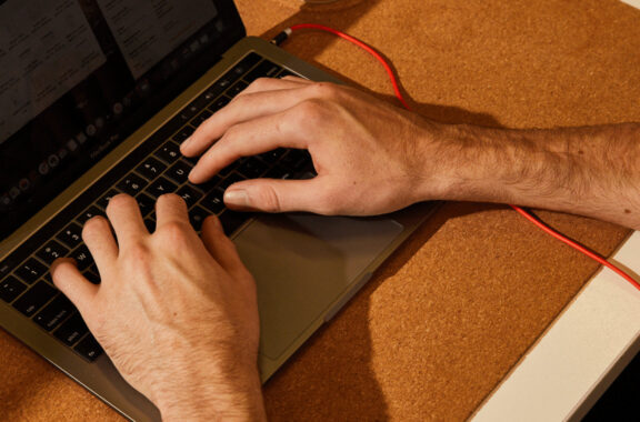 Close up of man's hands typing on a laptop