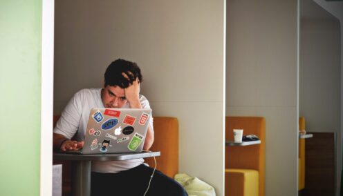 Man holding his head and looking at his laptop
