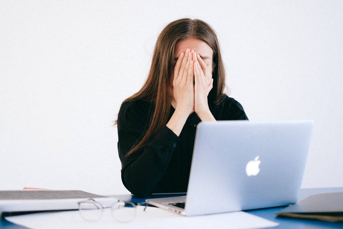 woman using computer with hands on her face