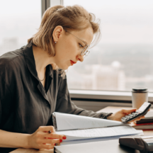 Woman using a calculator and manual calculations.