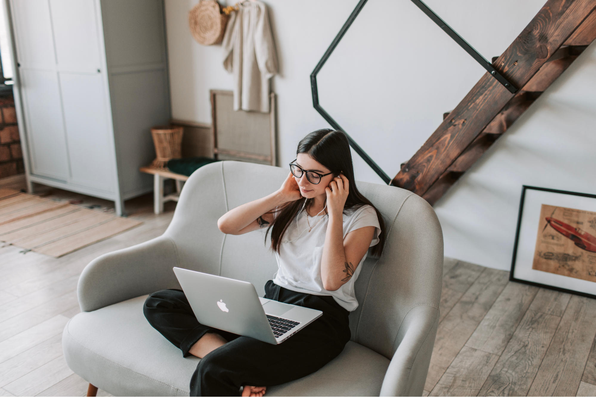 woman listening to music through headphones while seated on the couch