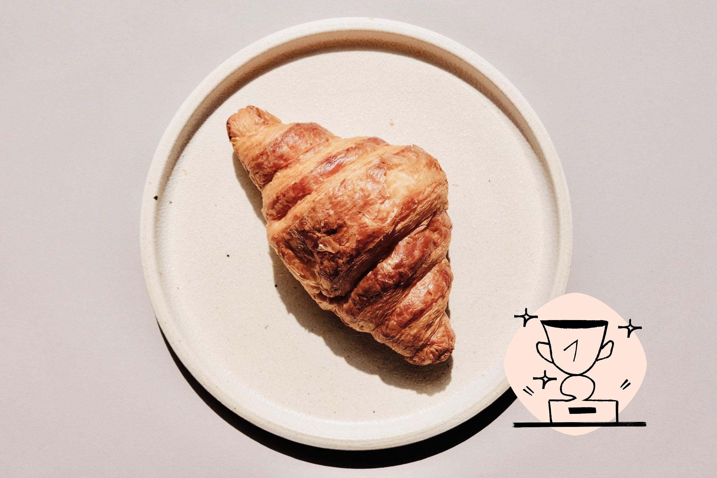 croissant on a plate with a number 1 trophy icon on the bottom right corner