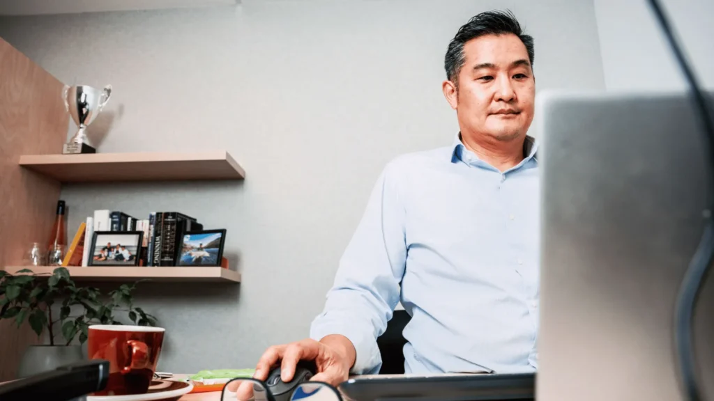 A male professional working on a laptop in a home office setting, representing how managers and HR teams can successfully facilitate the remote employee onboarding process.