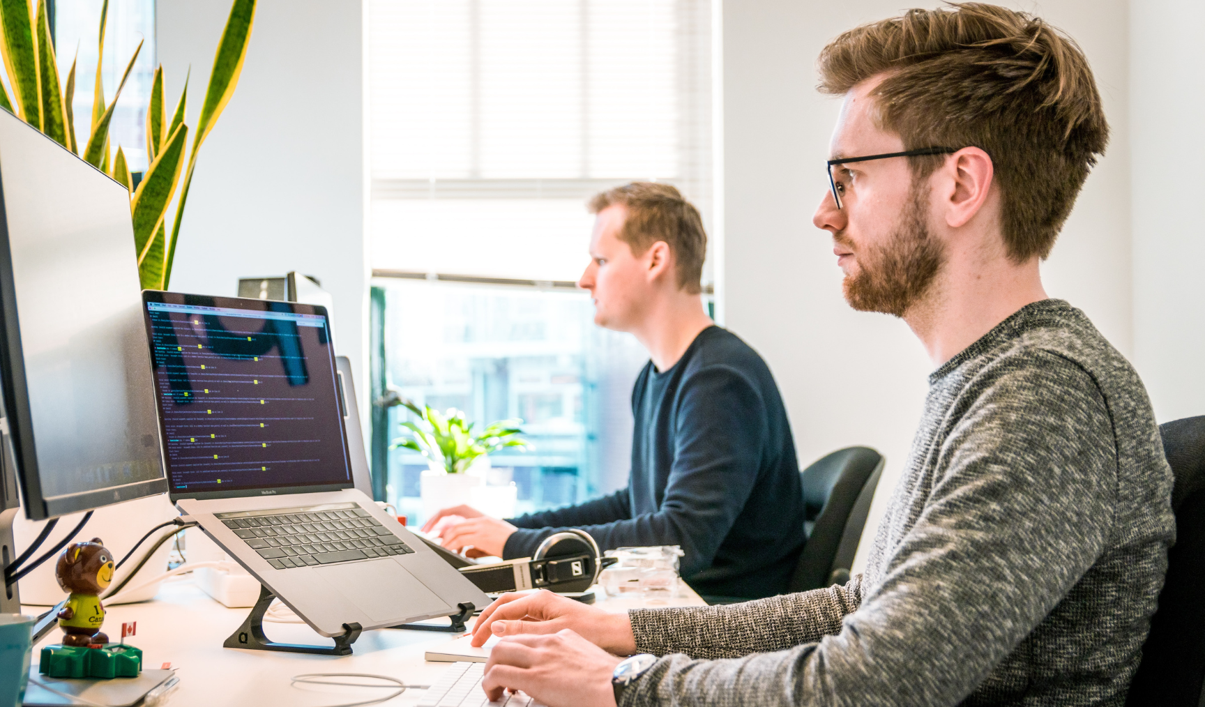 Two men sitting at their desks working on computers